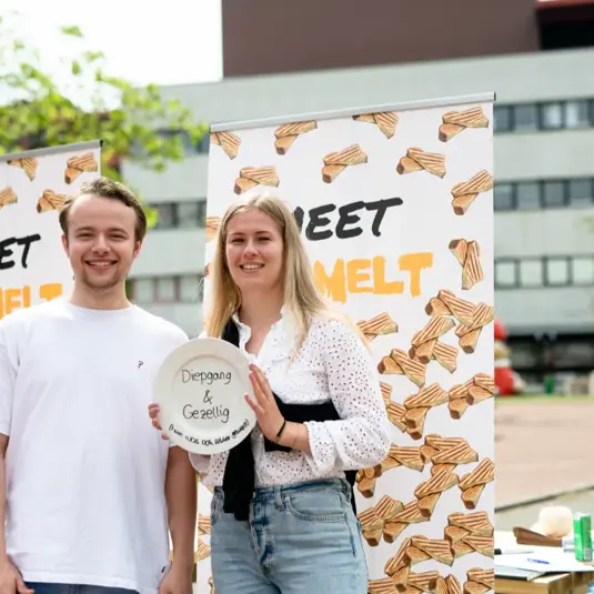 Foto van twee studenten voor banieren met 'Meet & Melt' erop