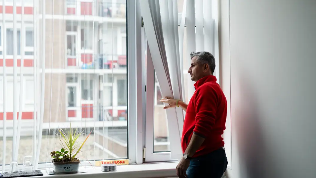 man kijkt uit raam